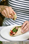 Frau träufelt Limettensaft auf Taco mit gegrilltem Flank Steak