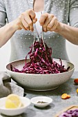 A woman is mixing a red cabbage salad