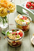 Pasta wheel salad with mozzarella cherry tomatoes and basil in the jar