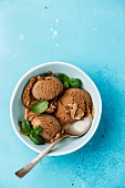Chocolate ice cream with mint leaf in bowl on blue background