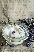 White sugar in glass jars flavored with lavender flowers, standing with tea spoon on table with sackcloth