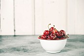 Fresh cherries in bowl on a rustic background