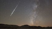 Meteor and Milky Way over desert, time-lapse footage