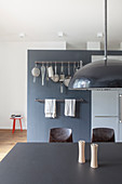 Black table in open-plan kitchen with hook rails mounted on grey wall