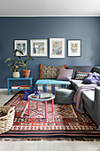 In Reihe gehängte Bilder an blauer Wand im Wohnzimmer mit Ethnoflair