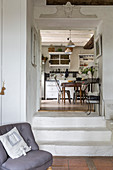 Easy chair with scatter cushion in front of open doorway leading into kitchen
