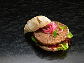 A hamburger with red onions and lettuce