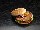 A hamburger in a sesame seed bun with onions, tomato, lettuce and ketchup