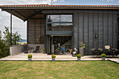 Rasen und Terrasse um ein modernes Haus mit dunkler Fassade