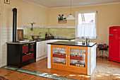 Island counter with glass cupboard doors in open-plan kitchen with antique cooker
