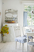 Blue ruffled cushions on chairs in white dining room