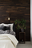 Houseplant on bedside table in front of wood-clad wall