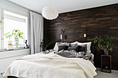 Mit dunklem Holz verkleidete Wand im winterlichen Schlafzimmer