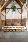 Flower arrangements suspended over set table in converted barn