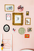 Galerie aus Bildern, Postkarten und Wandtellern an rosafarbener Wand