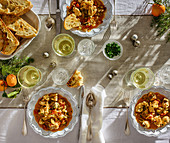 Fischeintopf mit Wein und Röstbrot auf gedecktem Tisch