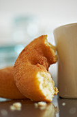 Half a doughnut next to a coffee mug