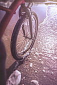 Bicycle wheel on beach at water's edge
