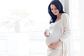 Pregnant woman touching tummy with milk