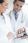 Male and female doctors using tablet
