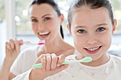 Mother and daughter brushing teeth