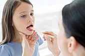 Female doctor examining inside girl's mouth