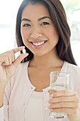 Woman holding pill and glass of water