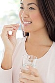 Woman holding pill and glass of water