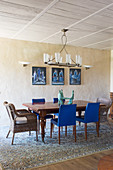 Chairs with blue upholstery and rattan armchairs around wooden table in dining room