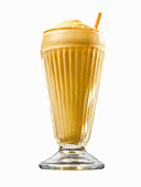 An orange creamsicle in a glass with a straw