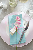 Place setting with pale blue linen napkin, flower and name card