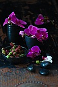 Pink orchids and unripe blackberries in black bowls
