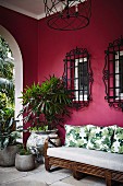 Sofa und Pflanzen auf einer Veranda mit pinker Wand und Fenstergittern