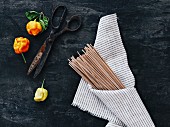 Uncooked whole-wheat fettucine wrapped in a cloth on a black background