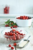 Sugar-coated Cornelian cherries in bowls next to a scoop full of sugar
