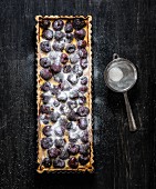 A rectangular cherry tart sprinkled with icing sugar