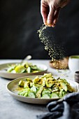 Seeds being sprinkled over a vegan mixed green salad
