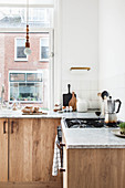 Simple kitchen in natural shades with wooden cabinets and marble worksurfaces