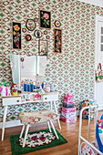 Upholstered stool, dressing table and stacked suitcases in girl's bedroom with retro wallpaper