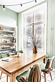 Table and chairs in front of window in dining area with green walls
