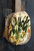 Wild garlic and asparagus pizza with parmesan on a pizza shovel (seen from above)