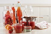 Schichtmarmelade aus Erdbeeren und Aprikosen im Glas, daneben frische Aprikosen und Erbeeren