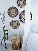 Wall decoration made of baskets over a tree trunk as a bedside table