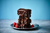 A stack of brownies with chocolate sauce and raspberries