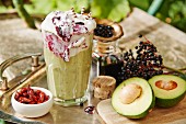 A smoothie with avocado, chili and elderberry frosting on a garden table