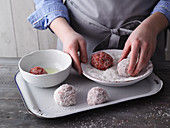 Meatballs being rolled in coconut flakes