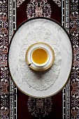 A cup of saffron chai on a lace doily (seen from above)