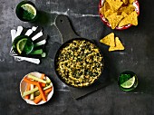 Spinach and artichoke dip with vegetable sticks and nachos
