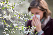 Woman with hay fever blowing her nose