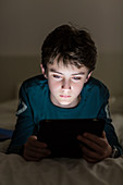 Teenage boy using a digital tablet at night